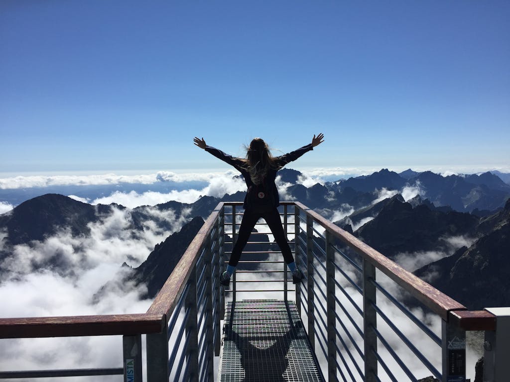 斯多葛主義是什麼?改變我人生的五個哲學觀念與名言 4 A woman stands on a viewing platform in Vysoké Tatry, Slovakia, surrounded by clouds and mountains, embracing freedom.