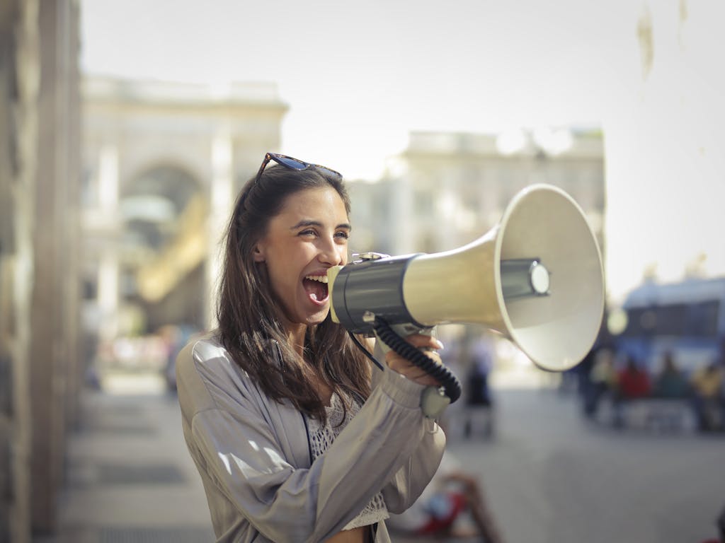 《愈忙愈要會表達》讀後心得:清楚表達的七個步驟 4 Cheerful young woman in a casual outfit shouting into a megaphone on a sunny day.