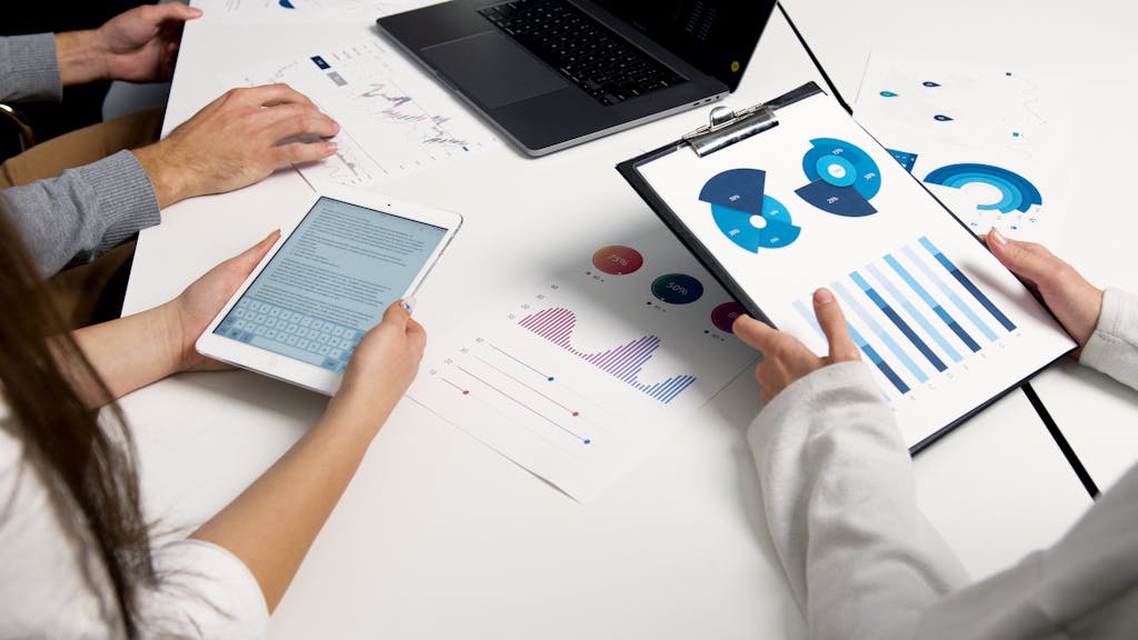 《阿甘投資法》讀後心得:一套簡單穩健的股票被動投資法 4 Team analyzing financial charts and digital reports during a business meeting.