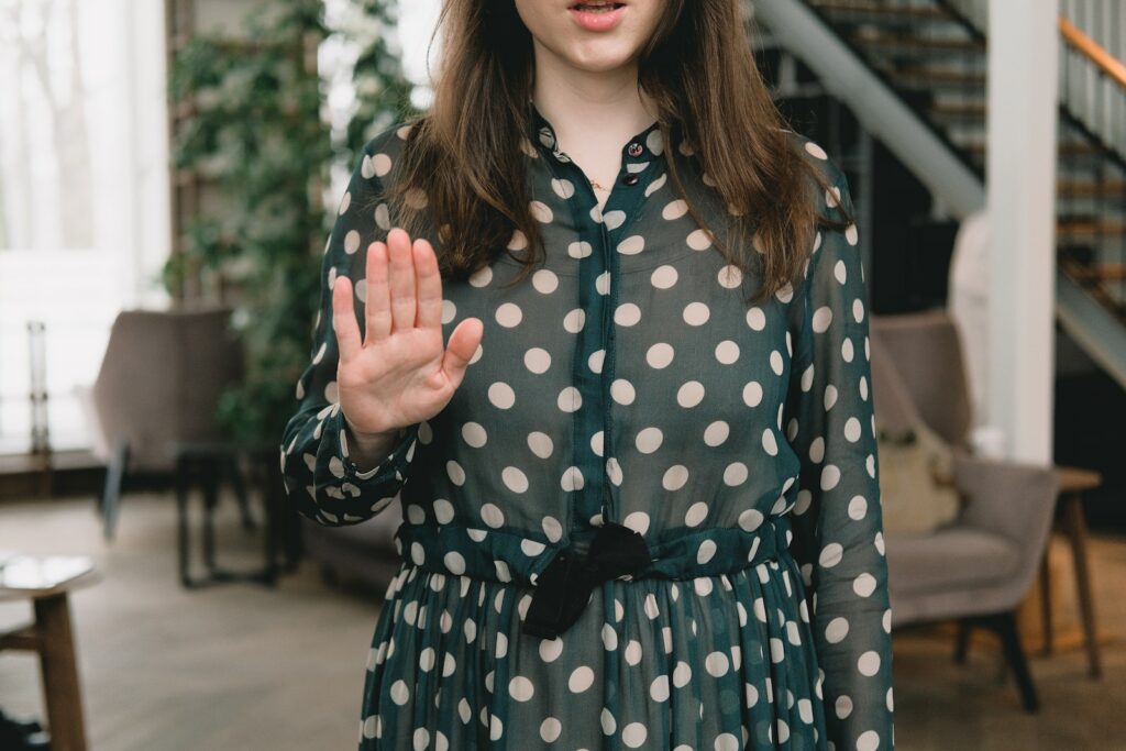 Crop feminine woman showing stop gesture in modern apartment