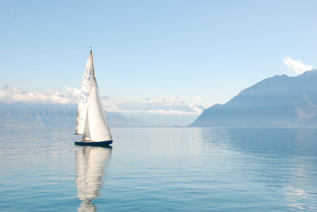 無聊的藝術:在失控的焦慮世代,無聊是最高級的叛逆 4 Sailing boat glides peacefully on a misty lake surrounded by mountains, under clear daylight.