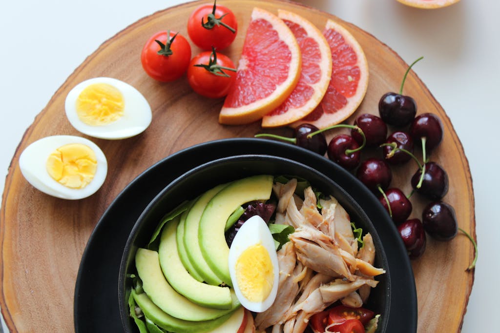 如何養成好習慣全攻略:4 個策略、6 大習慣教學、3 種行動 4 A vibrant, healthy salad bowl with avocado, eggs, tomatoes, grapefruit, and cherries on a wooden board.