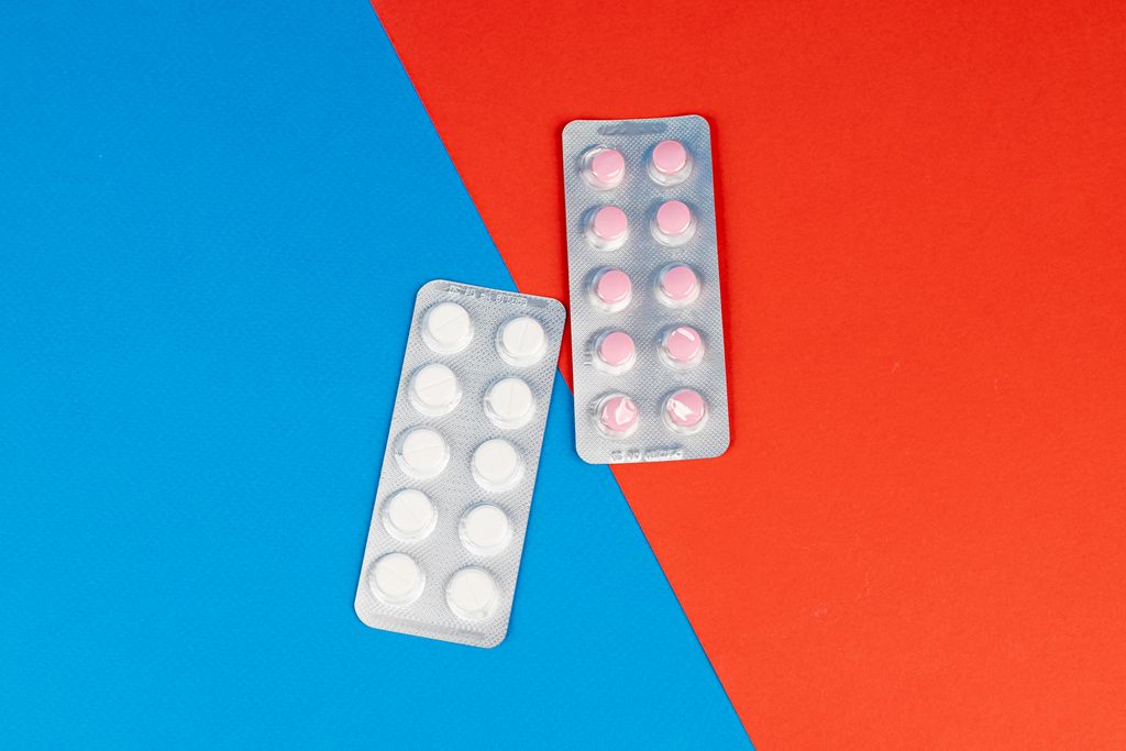 Flat lay of pill blister packs on a red and blue surface, ideal for healthcare themes.