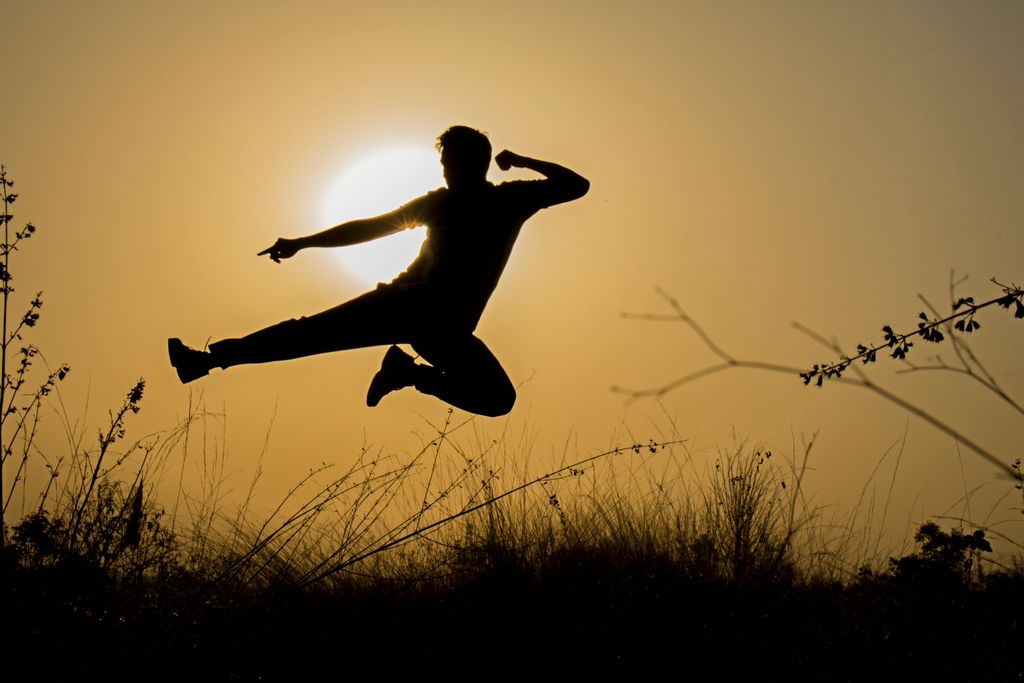 A dynamic silhouette of a man performing a jump against the sunset in Wadgaon, India.